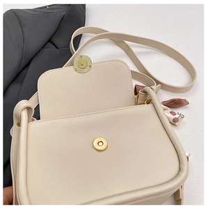 Detail of cream crossbody bag with gold magnetic buckle and floral silk scarf accessory