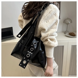 Close-up of black Hobo bag with silver metal grommets and rivets in a lifestyle setting