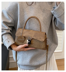 Detail of vintage brown textured handbag showing silver clasp and fashion metal tag