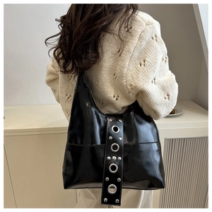 Détail du sac à épaule en cuir verni noir avec rivets vintage et œillets métalliques
