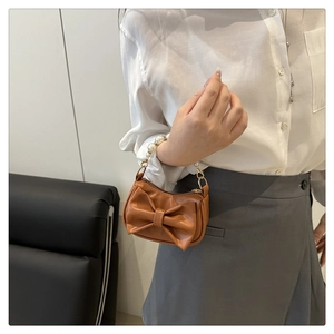 Detailed view of caramel mini bag with 3D bow and elegant white pearl handle
