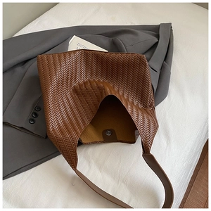 Gros plan détaillé du sac cabas en cuir tressé marron avec boucle magnétique et sangle