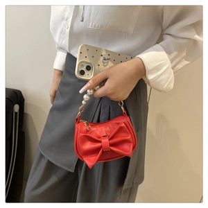 Detail of red bow handbag with elegant pearl handle and polished gold hardware accents