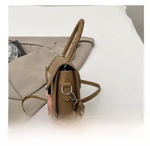 Detail of silver spring hook and D-ring attachment on brown textured crossbody bag