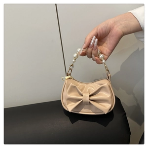 Close-up of beige mini handbag with large bow detail and faux pearl beaded handle