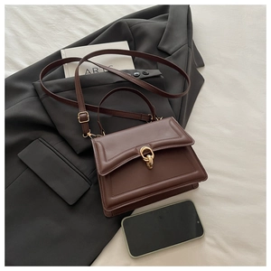 Détail de sac en cuir marron avec surpiqûres décoratives et fermoir en métal doré