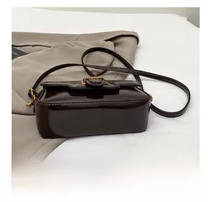 Gros plan détaillé du fond renforcé et du cuir brillant de ce sac marron foncé
