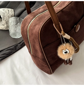 Detail of vintage brown suede bowling bag featuring a cute plush pendant accessory