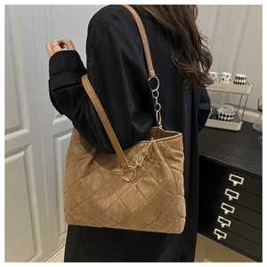 Close-up of quilted suede tote bag with diamond pattern and light gold chain strap