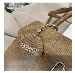Detailed view of brown textured crossbody bag featuring a round Fashion charm accessory