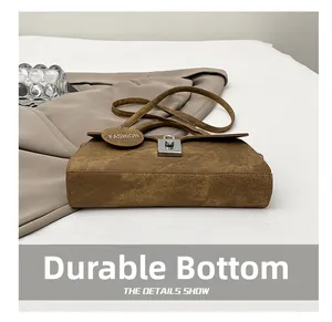 Close-up of wear-resistant bottom on a brown suede underarm bag with silver lock