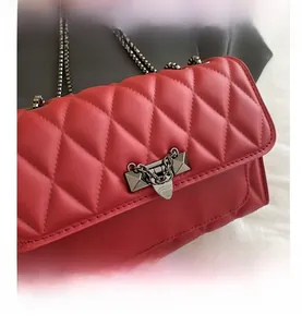 Detail shot of red quilted crossbody bag with silver rivet buckle and chain strap