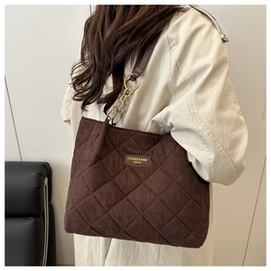 Detail der braunen Stepp-Tote-Bag mit goldener Kette auf beigem Trenchcoat