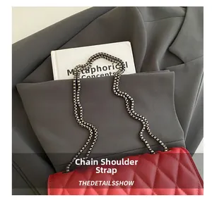 Detail of red quilted crossbody bag featuring a thick dark grey chain shoulder strap