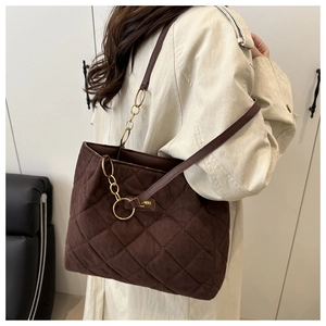 Detail view of large dark brown quilted tote bag with suede texture and chain strap