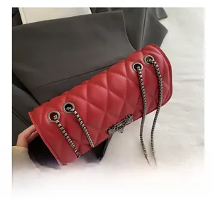 Macro detail of red quilted leather handbag with dark grey metal chain and grommets