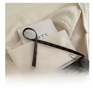 Detail of vintage brown monogram crescent bag featuring letter patterns and metal hooks