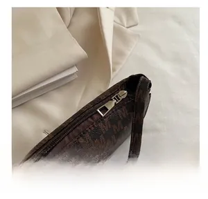 Close-up of smooth silver metal zipper on brown monogram crescent shoulder bag
