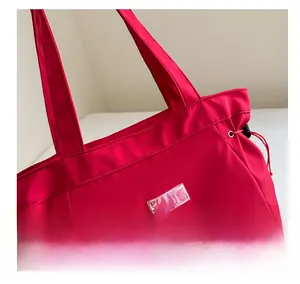 Detail of red tote bag featuring fashion label and adjustable side drawstring closure