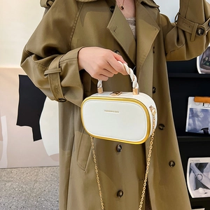 White box-shaped handbag with gold metal trim and chain strap, styled on beige trench coat