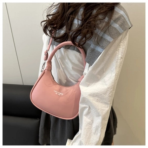 Detailed side view of pink crescent bag showing leather texture and white logo text