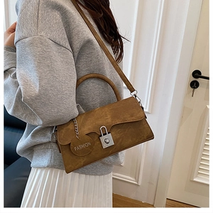 Close-up of brown leather handbag featuring a stylish wavy flap and decorative metal padlock