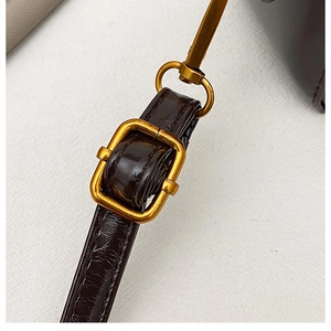 Détail macro de la bandoulière en cuir marron à motif croco avec boucle dorée vintage