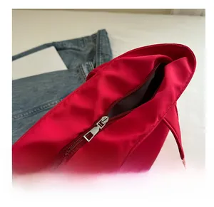 Detailed close-up of smooth silver metal zipper on a red canvas bag with fashion label
