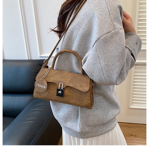 Detail of vintage brown textured leather shoulder bag with metal lock and fashion pendant