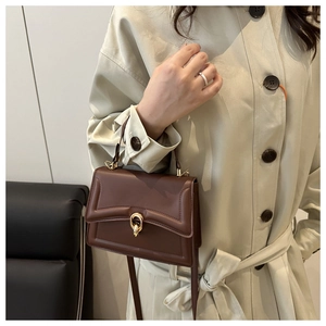 Détail du sac bandoulière marron foncé avec coutures ondulées et fermoir doré rond