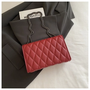 Gros plan d'un sac bandoulière rouge en cuir matelassé avec losanges et chaîne