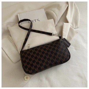 Detail of vintage brown letter pattern shoulder bag with silver hardware and leather tag