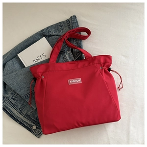 Detail of red drawstring tote bag with Fashion label next to denim jacket