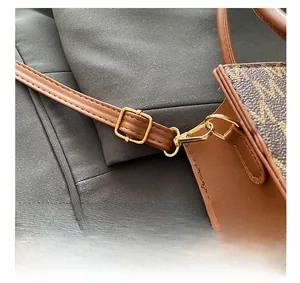 Detail of golden metal hooks and adjustable buckle on brown leather tote shoulder bag