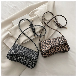 Detail of leopard print shoulder bags featuring knotted straps on a stylish cream blazer