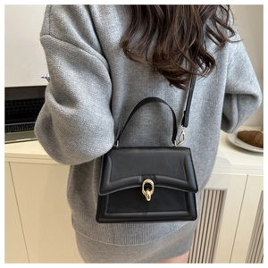 Détail d'un sac à main noir en cuir avec boucle dorée et finitions soignées