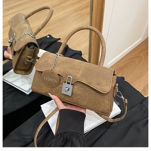 Detail of vintage brown textured leather handbag featuring silver lock and metal tag
