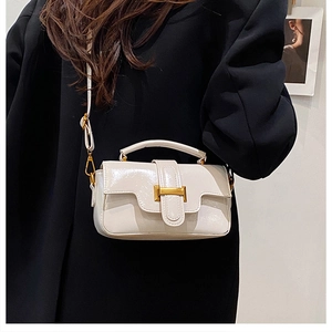 Détail d'un sac à bandoulière blanc brillant avec fermoir en H doré et poignée supérieure
