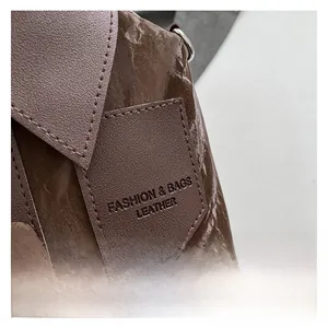 Macro shot of dark brown leather handbag featuring wrinkled texture and embossed fashion logo