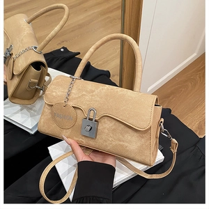 Detail of camel crossbody bag with silver padlock clasp and metallic fashion chain strap