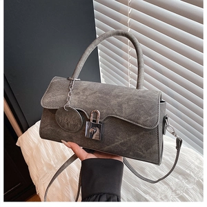 Detail of grey denim texture crossbody bag with silver metal buckle and fashion charm