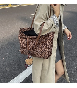Close-up of leopard print tote bag featuring brown handles and a cute plush bear charm
