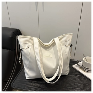 Detail view of white canvas tote bag with FASHION patch and side drawstring accents
