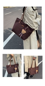 Detail of dark brown tote bag with bear charm and leather handles in outdoor setting