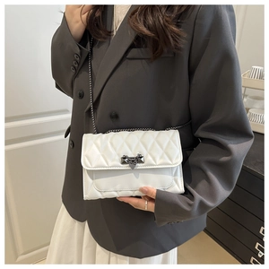 Close-up of white quilted leather texture with metallic chain and unique lock detail
