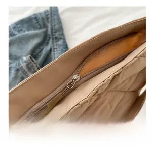 Vue macro détaillée de la fermeture éclair en métal et du motif matelassé du sac beige