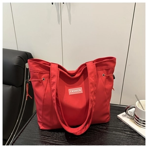 Close-up of red nylon tote bag with fashion label and drawstring detail on side
