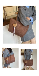 Detail of suede tote bag featuring debossed logo and a cute plush bear keychain