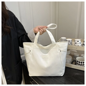 Detailed close-up of white tote bag with FASHION label and metal eyelet drawstring design
