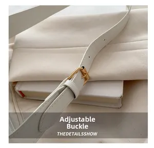 Detail of adjustable golden buckle and fine stitching on a white leather shoulder bag strap